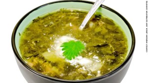 Green nettle soup in a bowl with a spoon isolated on white background
